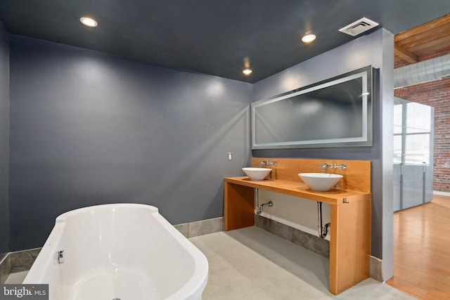 bathroom featuring a tub, wood-type flooring, vanity, and brick wall