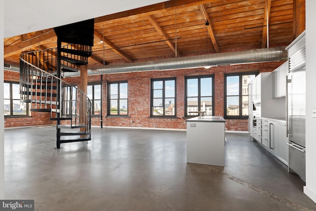 interior space featuring plenty of natural light, brick wall, and beam ceiling