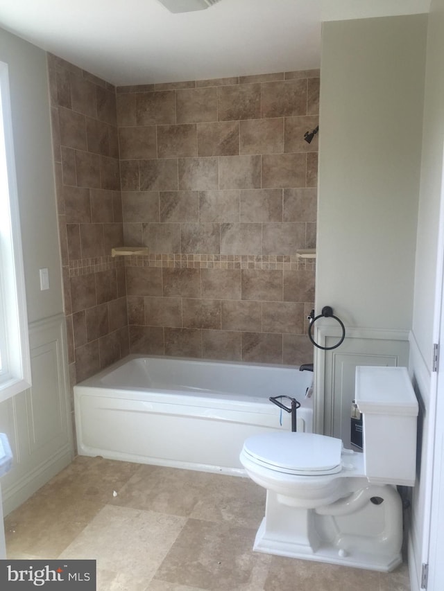 full bathroom with a wainscoted wall, toilet, and washtub / shower combination