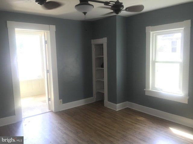 empty room featuring wood finished floors, a healthy amount of sunlight, baseboards, and ceiling fan