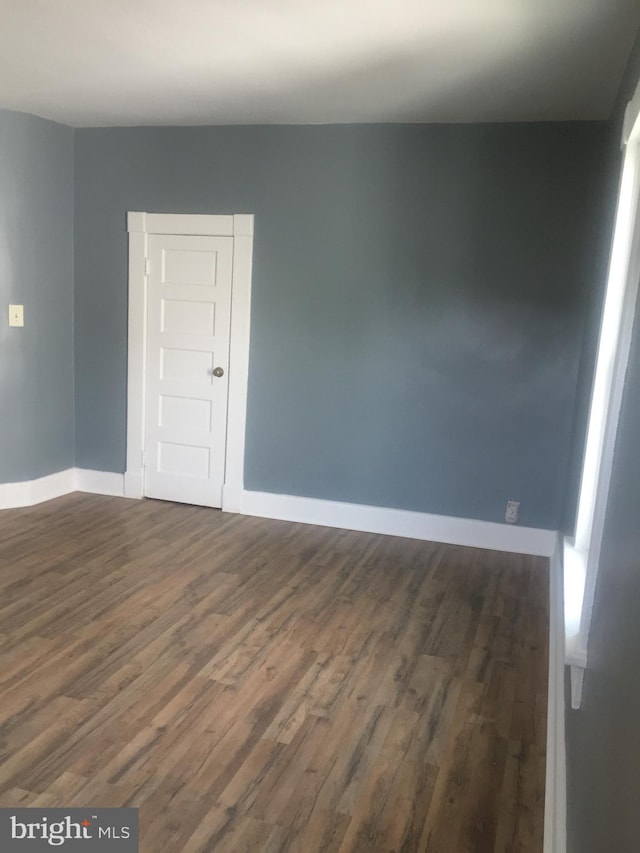 unfurnished room with dark wood-style floors and baseboards