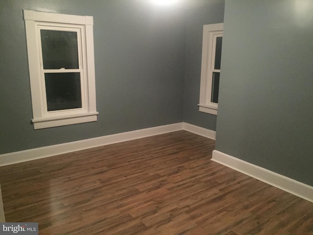 spare room featuring dark wood-style floors and baseboards