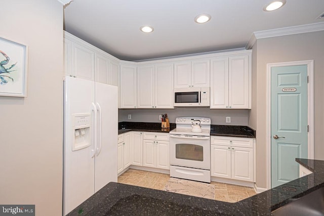 kitchen featuring crown molding, dark stone counters, white appliances, and white cabinets