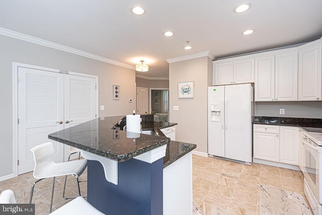 kitchen featuring dark stone countertops, crown molding, white cabinetry, white appliances, and a kitchen bar