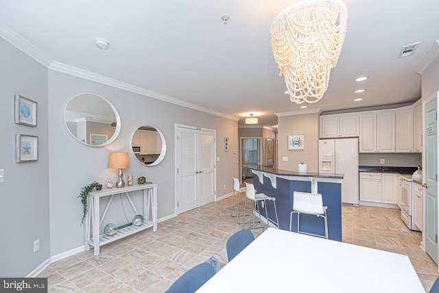 kitchen featuring white fridge with ice dispenser, a chandelier, a kitchen breakfast bar, a center island, and white cabinets