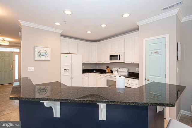 kitchen with a kitchen bar, dark stone countertops, and white appliances