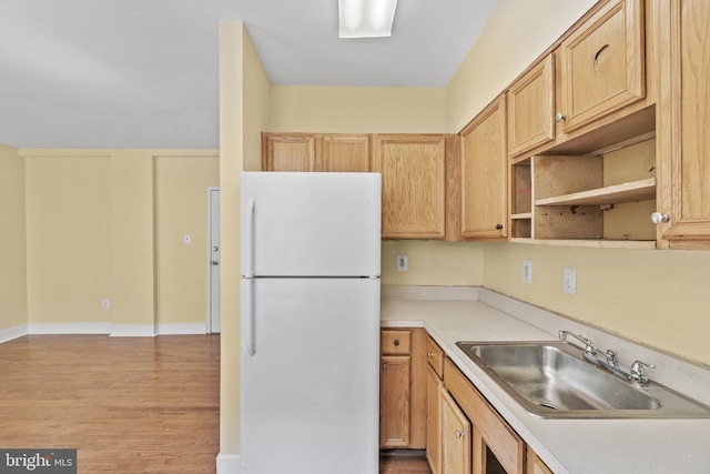 kitchen featuring white fridge, hardwood / wood-style flooring, light brown cabinets, and sink