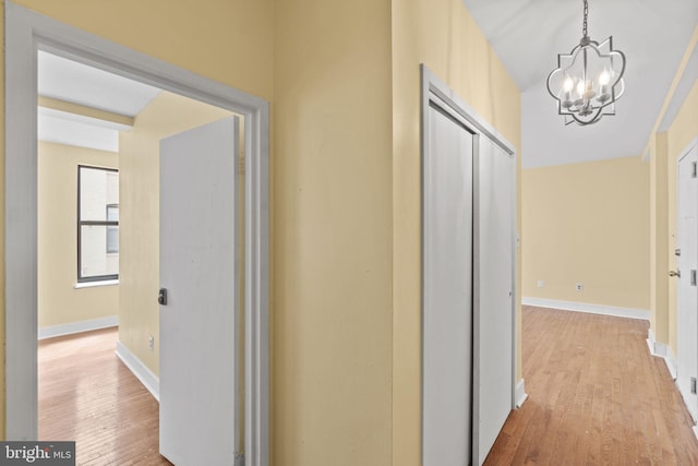 corridor with an inviting chandelier and light wood-type flooring