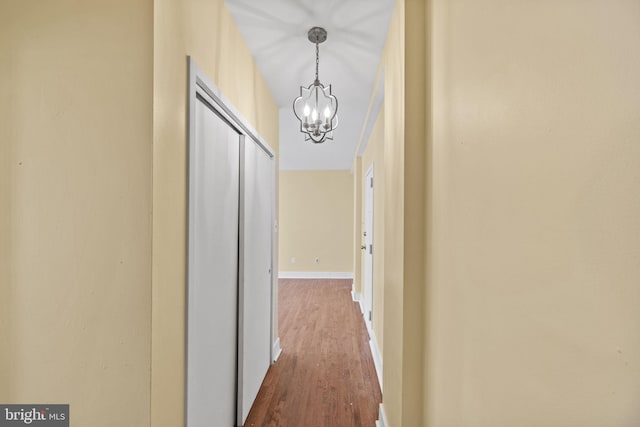 hall with wood-type flooring and an inviting chandelier