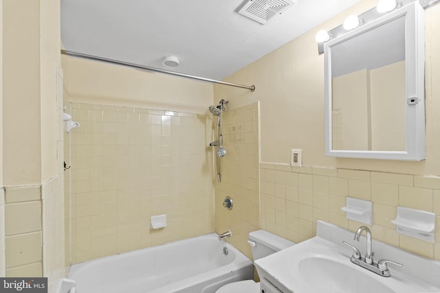 full bathroom featuring backsplash, toilet, tile walls, tiled shower / bath combo, and vanity