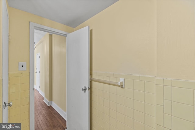 hall featuring dark wood-type flooring and tile walls