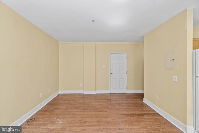 spare room featuring electric panel and hardwood / wood-style floors