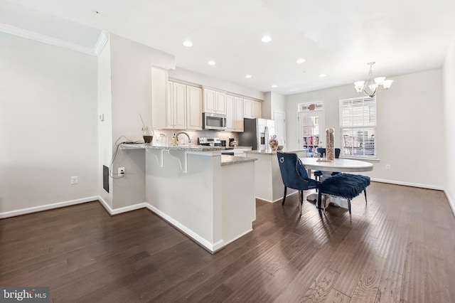 kitchen featuring a peninsula, light stone countertops, dark wood-type flooring, and stainless steel appliances