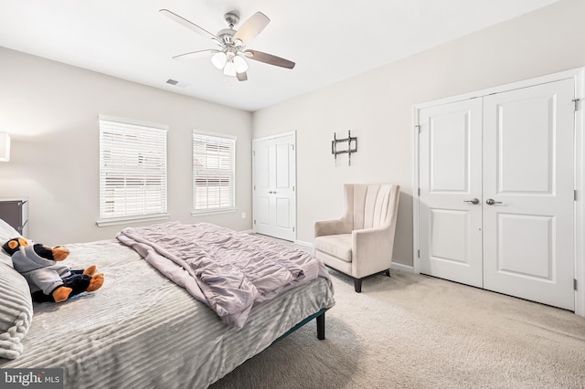 bedroom featuring visible vents, light carpet, two closets, baseboards, and ceiling fan