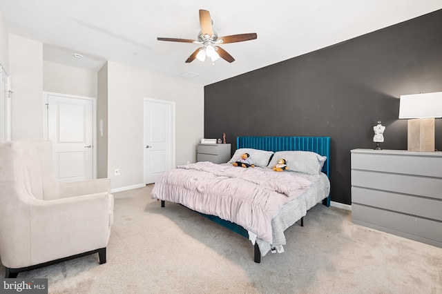 bedroom with baseboards, an accent wall, carpet, and a ceiling fan