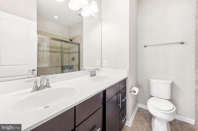 bathroom featuring double vanity, a stall shower, toilet, and a sink