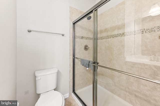 full bathroom featuring tile patterned floors, baseboards, toilet, and a shower stall