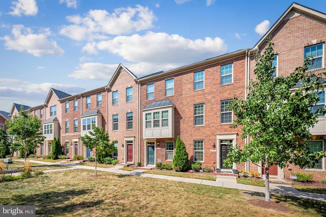 view of property with a front lawn and brick siding