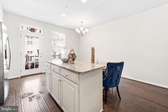 kitchen with dark wood-style floors, white cabinetry, a kitchen island, a kitchen bar, and stainless steel fridge