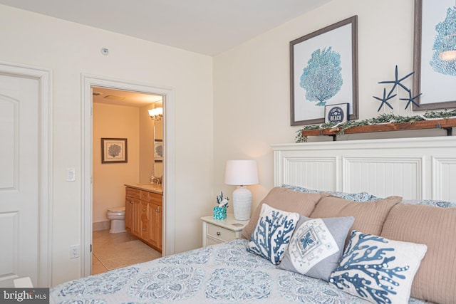 bedroom with light tile patterned flooring, ensuite bathroom, and a sink