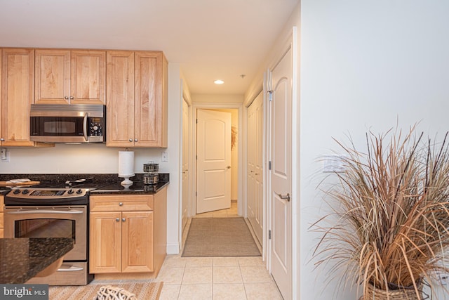 kitchen with stainless steel appliances, dark stone countertops, and light tile patterned floors