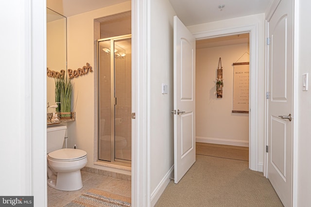 bathroom with tile patterned flooring, toilet, and a shower with shower door