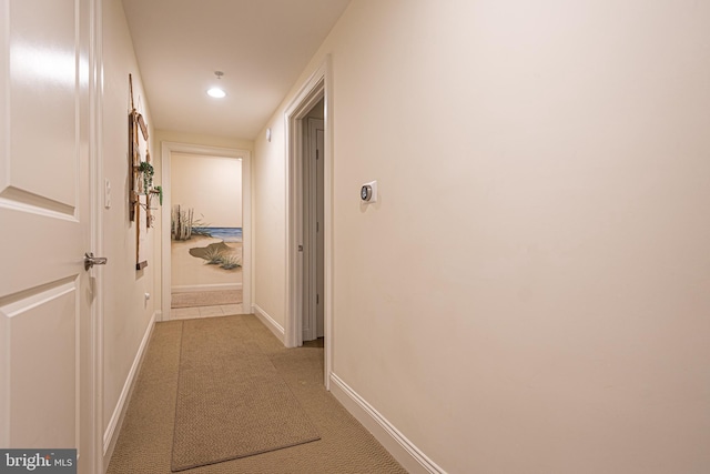 hallway with recessed lighting, light colored carpet, and baseboards