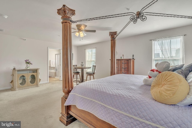 bedroom featuring ceiling fan, light colored carpet, and ensuite bath