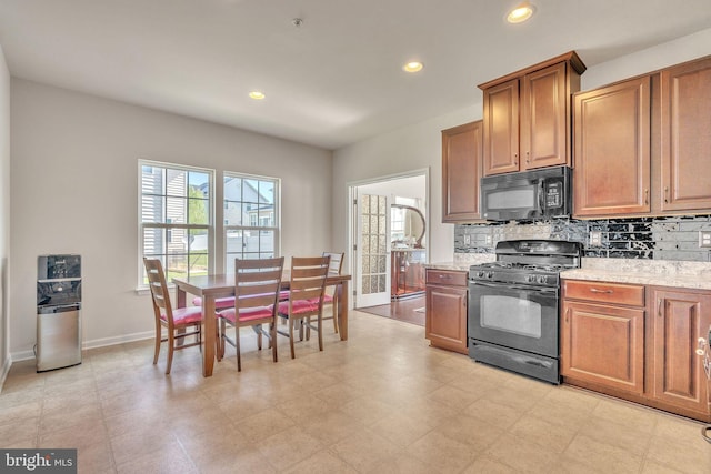 kitchen featuring black appliances, backsplash, and light stone countertops