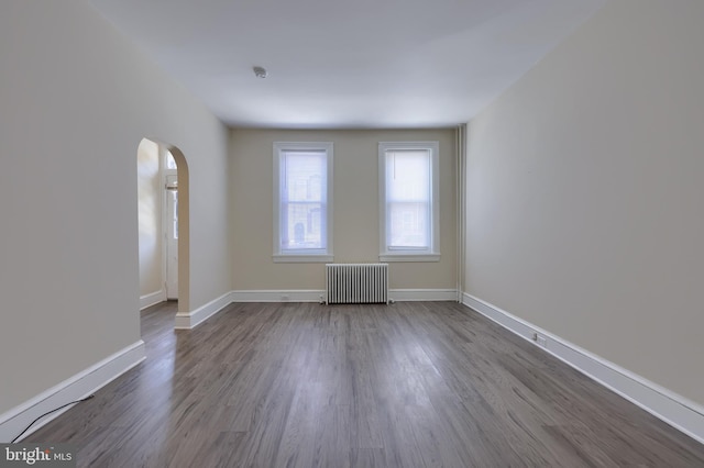 spare room with radiator heating unit and wood-type flooring