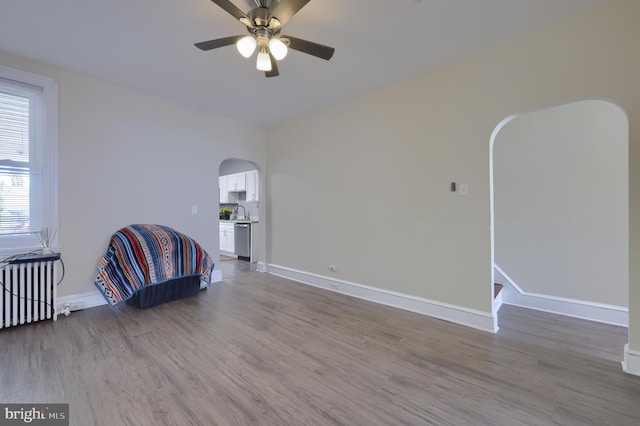 unfurnished room with hardwood / wood-style floors, ceiling fan, and radiator