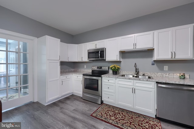 kitchen featuring appliances with stainless steel finishes, white cabinetry, wood-type flooring, and sink