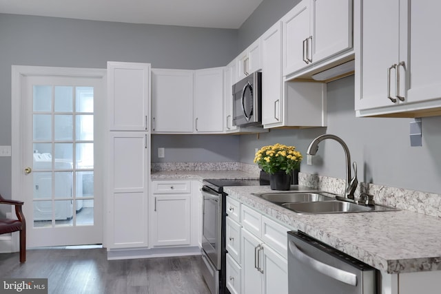 kitchen with dark wood-type flooring, white cabinets, and appliances with stainless steel finishes