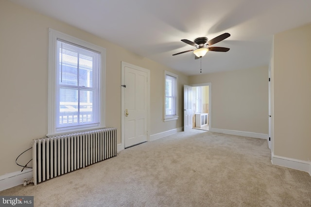 entrance foyer featuring light colored carpet, ceiling fan, and radiator heating unit