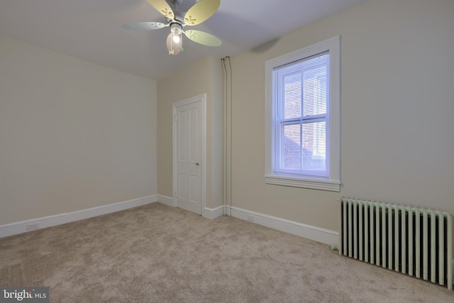 carpeted spare room with radiator heating unit and ceiling fan