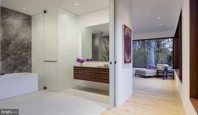 bathroom featuring a tub, vanity, tile walls, and hardwood / wood-style flooring