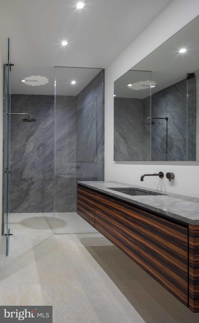 bathroom with a tile shower, tile walls, and vanity