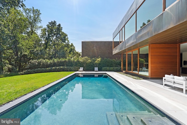 view of pool with a patio and a lawn