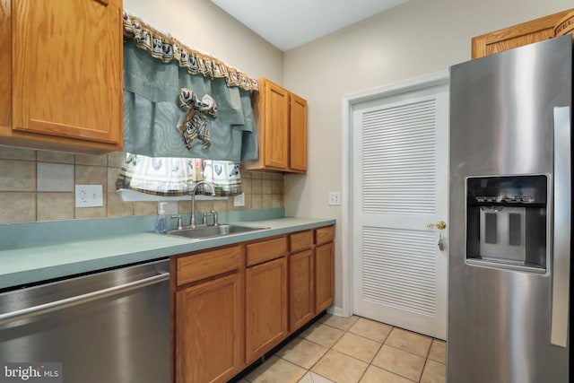 kitchen with appliances with stainless steel finishes, light tile patterned flooring, sink, and tasteful backsplash