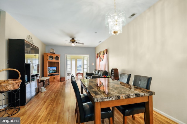 dining room with ceiling fan with notable chandelier and light hardwood / wood-style floors