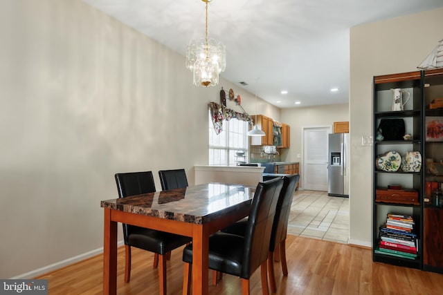 dining area with light wood-type flooring and a notable chandelier