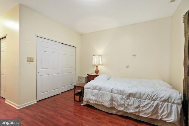 bedroom with dark wood-type flooring and a closet