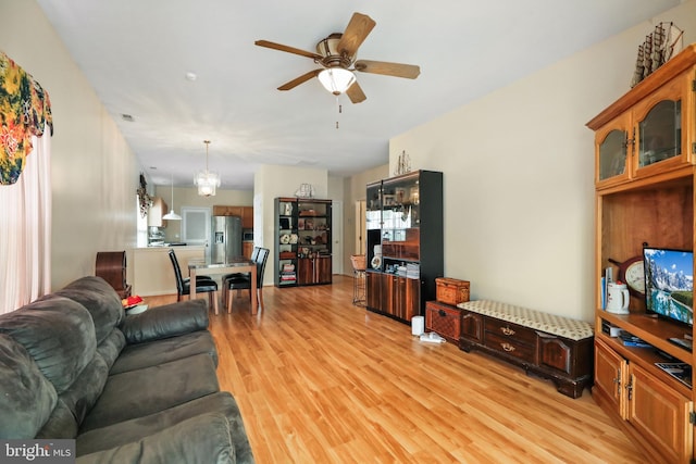 living room featuring ceiling fan with notable chandelier and light wood-type flooring