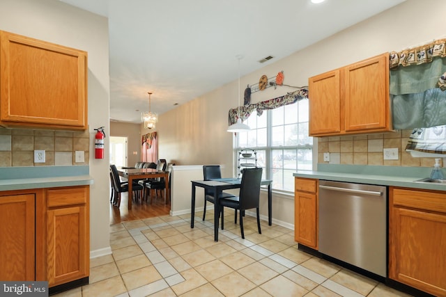 kitchen featuring tasteful backsplash, light tile patterned flooring, hanging light fixtures, an inviting chandelier, and dishwasher