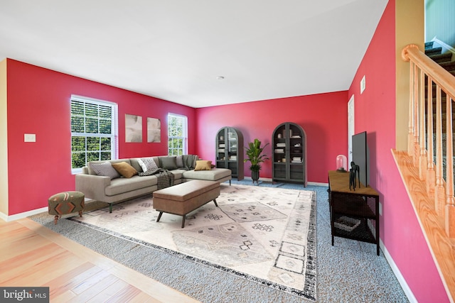 living area with visible vents, wood finished floors, stairs, baseboards, and an accent wall