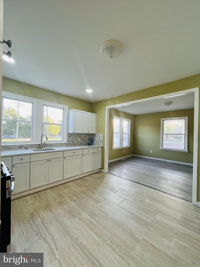 kitchen featuring light hardwood / wood-style flooring, white cabinets, range, and sink