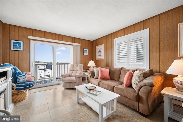 living area featuring light tile patterned floors, wooden walls, and a textured ceiling