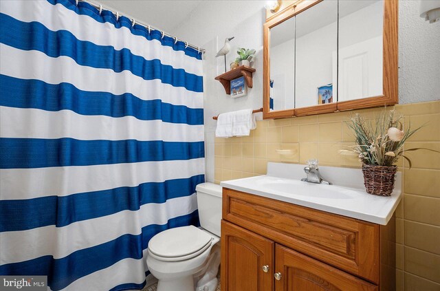 bathroom featuring toilet, curtained shower, tile walls, and vanity