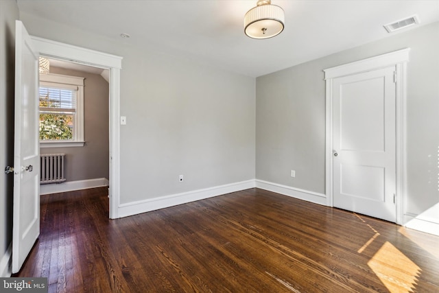 spare room featuring radiator heating unit and dark hardwood / wood-style floors