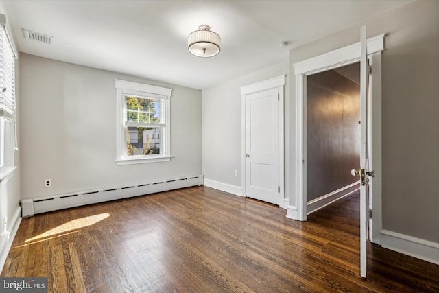 unfurnished bedroom featuring a baseboard heating unit and dark hardwood / wood-style flooring